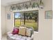 Cozy sitting area features a wicker chair with pillows and a large window overlooking a lush green landscape at 5729 Avista Dr, Sarasota, FL 34243