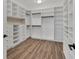 This walk-in closet features white storage shelves, drawers, hanging racks, and wood-look floors at 5833 Millennium Silver Ct, Sarasota, FL 34238