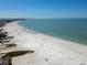 An aerial view of a sandy beach near clear, blue ocean water on a sunny day at 5855 Midnight Pass Rd # 204, Sarasota, FL 34242