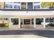 Inviting building entrance featuring a covered entryway with pillars, lush landscaping and a secure glass doorway at 5855 Midnight Pass Rd # 204, Sarasota, FL 34242