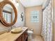 Bathroom featuring a round mirror over the sink, neutral color scheme, and a tiled shower with a curtain at 6308 Caracara St, Sarasota, FL 34241