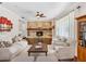 Cozy living room featuring a stone fireplace, hardwood floors, light furniture, and a ceiling fan at 6308 Caracara St, Sarasota, FL 34241