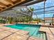 Inviting screened-in pool with brick patio and views of the surrounding greenery and blue skies at 6308 Caracara St, Sarasota, FL 34241