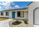 Close-up of a home's entrance with a vibrant blue door, fresh flowers, and tidy landscaping at 7002 Primm Pl, North Port, FL 34287