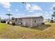 Daytime angled shot of a tan home with a grassy lawn and partial shrubbery under a bright blue sky at 8517 Buckingham Pl, Palmetto, FL 34221