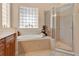 Elegant bathroom featuring a garden tub, glass-enclosed shower and frosted glass window at 9818 Portside Ter, Bradenton, FL 34212