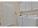 Practical laundry room equipped with a washer, dryer, and overhead storage cabinets at 9818 Portside Ter, Bradenton, FL 34212
