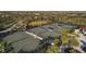 View of tennis courts in a community with green surface, dark fencing, and shaded rest areas at 16436 Daysailor Trl, Lakewood Ranch, FL 34202