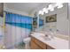 A well-lit bathroom featuring a vanity with a mirror and sink, and a shower with a blue curtain at 113 Palm Ave, Anna Maria, FL 34216