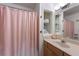 A cozy bathroom featuring a vanity with a mirror and sink, and a shower with a pink curtain at 113 Palm Ave, Anna Maria, FL 34216