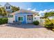 Charming blue bungalow featuring a brick driveway, white picket fence, and coastal-themed decor at 113 Palm Ave, Anna Maria, FL 34216