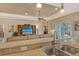 View from the kitchen into the living room with a large TV, ceiling fan, and sliding glass doors at 11723 Cullen Park Ter, Bradenton, FL 34211