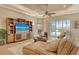 Comfortable living room featuring a large TV, ceiling fan, and sliding glass doors to the outdoors at 11723 Cullen Park Ter, Bradenton, FL 34211