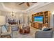 Open-concept living room with tray ceilings, entertainment center, and view of the dining area and front door at 11723 Cullen Park Ter, Bradenton, FL 34211