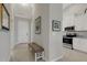 Inviting hallway with a bench leading to a kitchen with stainless appliances and white cabinets at 12405 Osorio Ct # 202, Sarasota, FL 34238