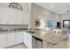 Well-lit kitchen boasting granite countertops, white cabinetry and stainless steel dishwasher at 12405 Osorio Ct # 202, Sarasota, FL 34238