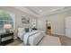 Well-lit bedroom featuring a tray ceiling, wood flooring, and access to an en-suite bathroom at 14404 Stirling Dr, Lakewood Ranch, FL 34202