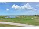 Picturesque golf course with a winding cart path, serene lake, and mature trees under a partly cloudy sky at 14404 Stirling Dr, Lakewood Ranch, FL 34202