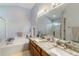 Bright bathroom featuring a double sink vanity, large mirror, and separate tub and shower at 16620 Fairbolt Way, Odessa, FL 33556