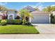 Charming single-story home featuring well-manicured lawn, palm trees, and a gray two-car garage at 16620 Fairbolt Way, Odessa, FL 33556