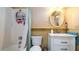 Bathroom featuring a shower-tub combo, decorative wallpaper, single sink vanity, and an oval mirror at 1770 Lake Pl # 1770D, Venice, FL 34293