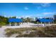 Sandy beach featuring blue canopies, palm trees, and nearby condominium complex under a sunny sky at 1928 Harbourside Dr # 1404, Longboat Key, FL 34228