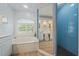 This bathroom has a soaking tub, a blue tiled shower, a window with shutters, and a large vanity at 1975 White Feather Ln, Nokomis, FL 34275