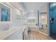 This bathroom offers a soaking tub, separate shower with blue tile, and dual sinks with white cabinetry at 1975 White Feather Ln, Nokomis, FL 34275