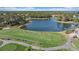 Aerial view of a golf course with a lake and people practicing their swings on a sunny day at 1975 White Feather Ln, Nokomis, FL 34275
