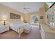 This main bedroom features a ceiling fan, a television, a pool view, and a king bed with a white frame at 1975 White Feather Ln, Nokomis, FL 34275