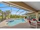 Screened-in pool and spa surrounded by seating and lush landscaping with views to the golf course at 1975 White Feather Ln, Nokomis, FL 34275