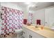 A well-lit bathroom with single sink vanity, tile flooring, and a shower with a colorful polka-dot curtain at 2620 White Sands Dr, Sarasota, FL 34231