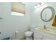Bright half bathroom features a vanity with sink, toilet, and round mirror at 2629 Rolling Rd, North Port, FL 34288