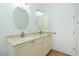 Bright bathroom with double vanity, cream-colored cabinets, granite countertop, and round mirrors at 2629 Rolling Rd, North Port, FL 34288