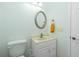 Half bathroom featuring a toilet, vanity with sink, and a round mirror at 2629 Rolling Rd, North Port, FL 34288