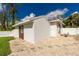 Rear exterior view of white house with brown door and a well maintained rock and grassy yard at 2629 Rolling Rd, North Port, FL 34288