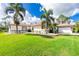 Charming single-story home with well-manicured lawn and lush landscaping featuring palm trees at 2629 Rolling Rd, North Port, FL 34288