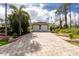 Spacious two-car garage with a long paver driveway, complemented by green landscaping and beautiful greenery at 2629 Rolling Rd, North Port, FL 34288