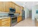Bright kitchen featuring stainless steel appliances, granite countertops, and natural wood cabinetry at 2629 Rolling Rd, North Port, FL 34288