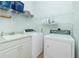 Bright laundry room with white washer and dryer, a sink, and storage shelves at 2629 Rolling Rd, North Port, FL 34288
