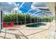Screen-enclosed pool features brick surround, two lounge chairs, and tropical landscaping at 2629 Rolling Rd, North Port, FL 34288