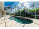 Screened-in pool featuring a brick surround and lush tropical landscaping at 2629 Rolling Rd, North Port, FL 34288
