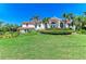 Lush landscaping frames this elegant two-story home with a terracotta tile roof on a manicured lawn under a clear blue sky at 3303 Sabal Cove Cir, Longboat Key, FL 34228