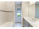 Well-lit bathroom featuring a modern vanity, tiled walls, shower and a window for natural light at 344 Maraviya Blvd, Nokomis, FL 34275
