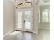 Bright foyer featuring decorative glass double doors, a crystal chandelier, wood-look tile floors, and natural light at 344 Maraviya Blvd, Nokomis, FL 34275