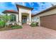 Elegant home exterior featuring a terracotta roof, paver driveway, manicured landscaping, and a two-car garage at 344 Maraviya Blvd, Nokomis, FL 34275
