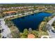 Aerial view of a community featuring a tranquil pond reflecting the blue sky, surrounded by lush trees and houses at 3736 82Nd Avenue E Cir # 104, Sarasota, FL 34243