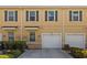 Townhome exterior with a yellow facade, dark shutters, a garage, and neatly landscaped bushes at 3736 82Nd Avenue E Cir # 104, Sarasota, FL 34243