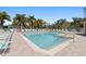 A spacious community pool area with ample lounge chairs, palm trees, and a clear blue sky above at 3736 82Nd Avenue E Cir # 104, Sarasota, FL 34243