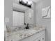 Well-lit bathroom with granite countertop, decorative light fixture, and framed mirror at 3857 Woodrow Ridge St, Sarasota, FL 34233